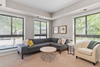 a living room with a couch and two chairs and two windows